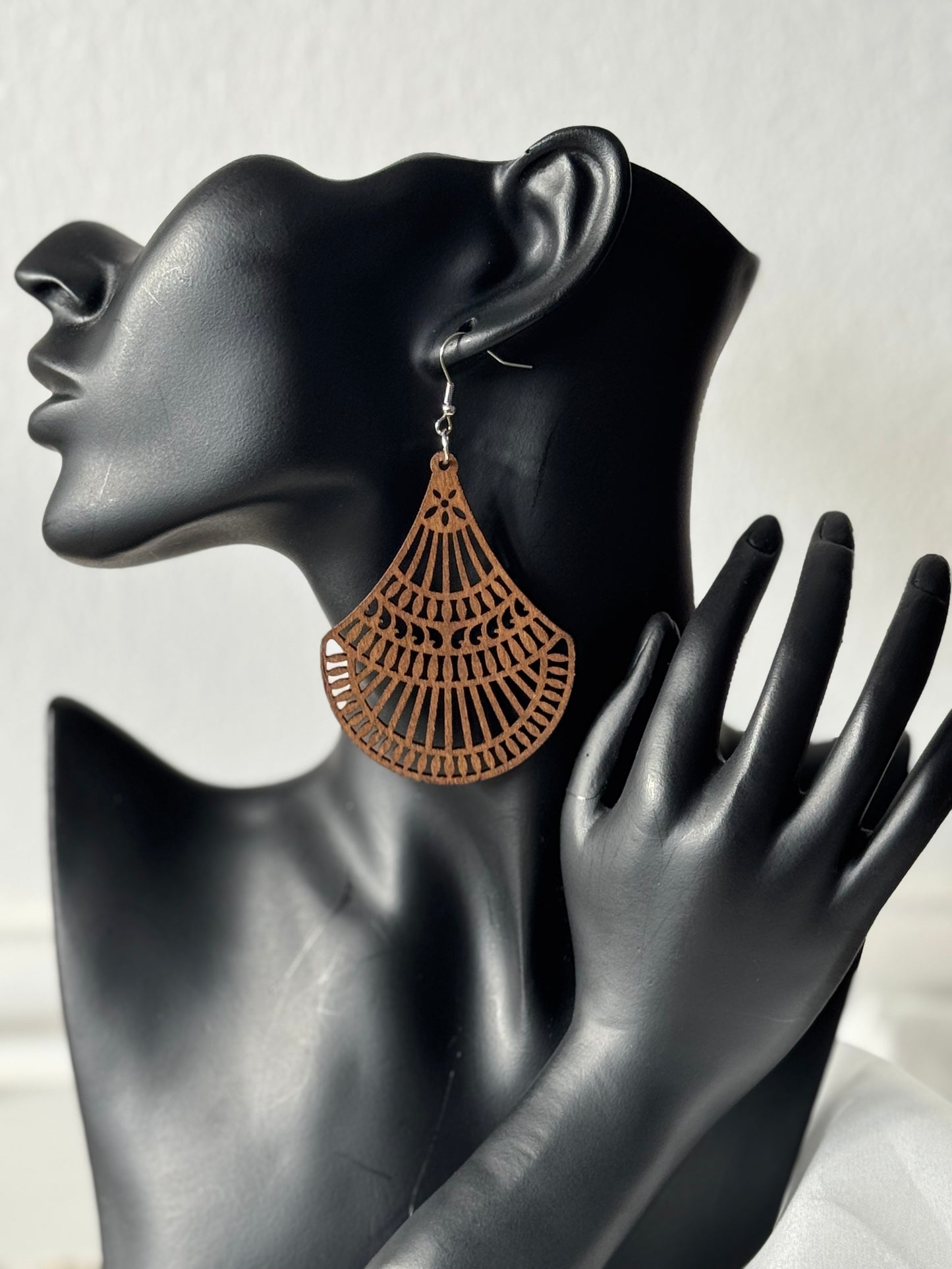 Wooden earrings with cut out design on a white fabric background