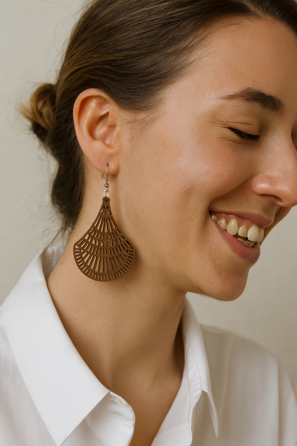 Wooden earrings with cut out design on a white fabric background