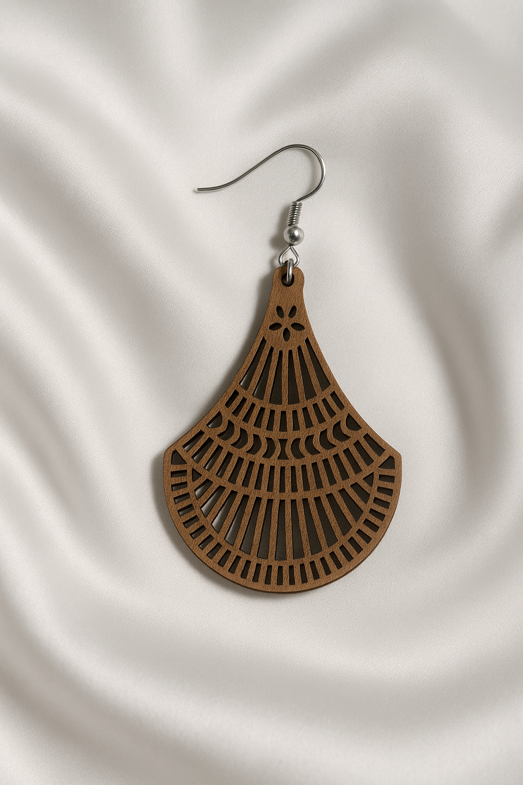Wooden earrings with cut-out design on a white fabric background